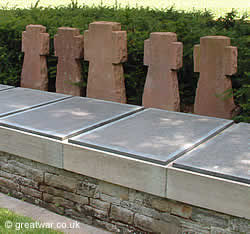 Five stone crosses next to the plaques bearing the names of soldiers buried in the Communal Grave.