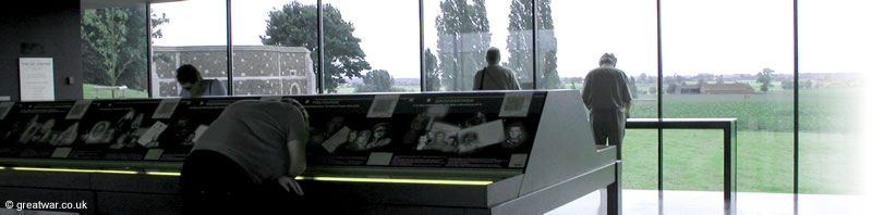 Inside the Visitors Centre looking through the panoramic window to the west and the city of 
		Ypres. The northernmost corner wall of Tyne Cot cemetery can be seen on the left.